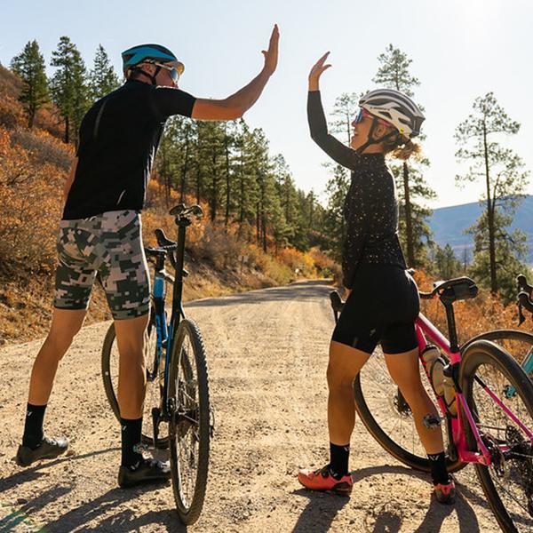 A woman and a man high-fiving after a bike ride. Shop women's socks