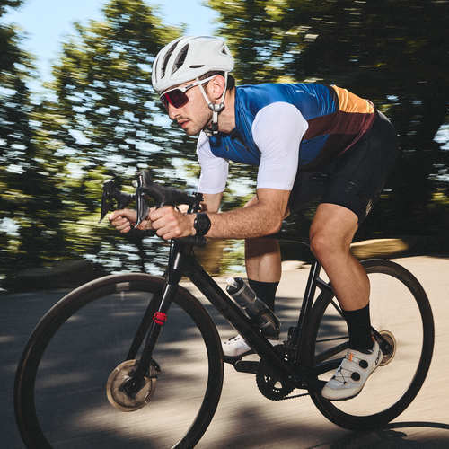 Cyclist riding their bike down a shaded road. Shop cycling socks.