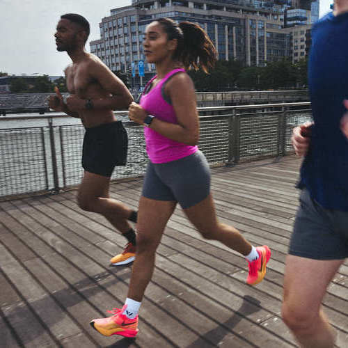 Three people running on a wooden pier in a city. Shop running socks.